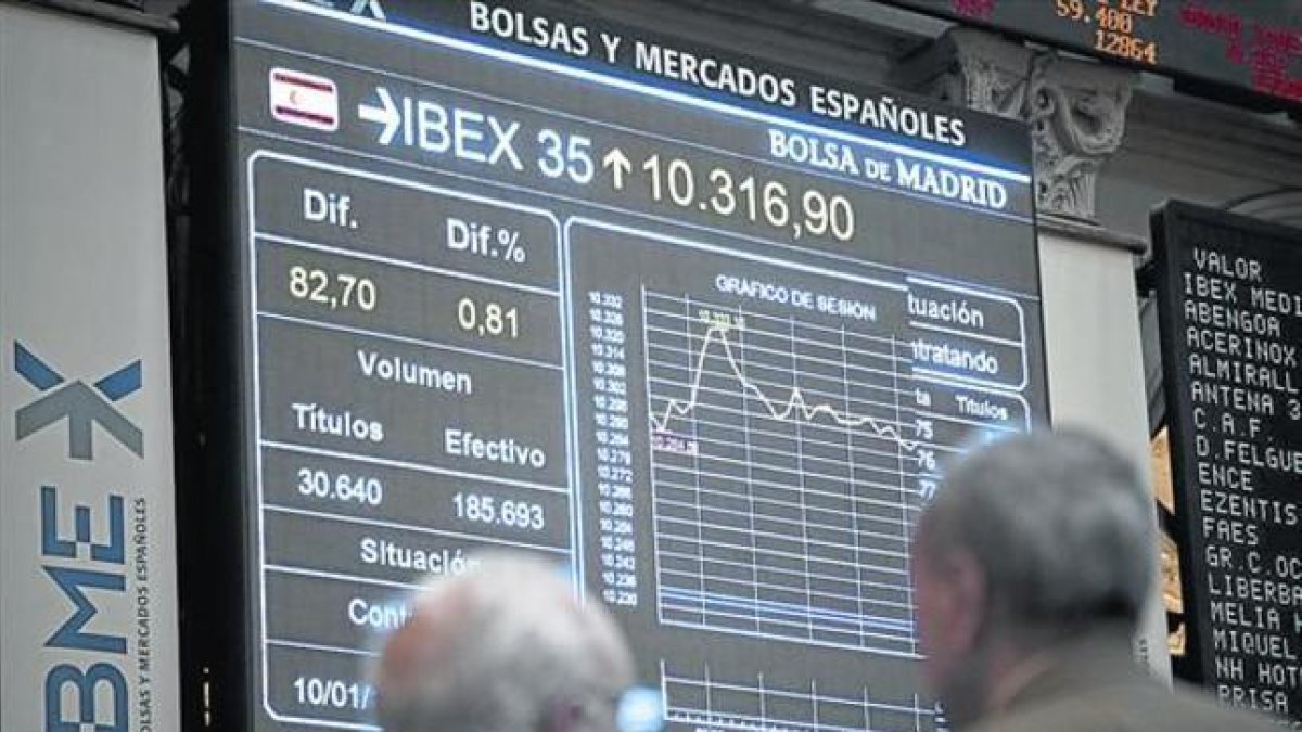 Dos inversores observan una pantalla con la evolución del Ibex 35 en la Bolsa de Madrid.-ARCHIVO / EFE