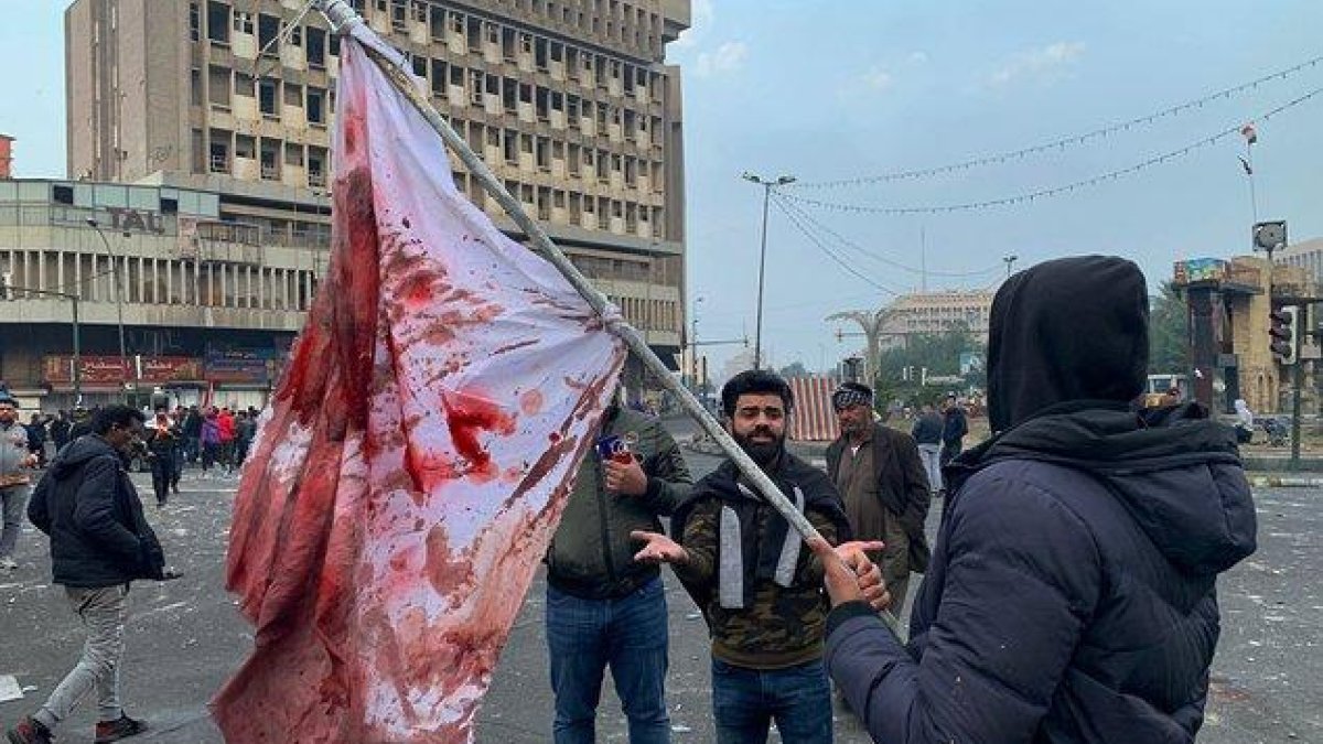 Manifestantes sostienen una bandera manchada de sangre tras el ataque en la plaza Al Jalani de Bagdad.-AP