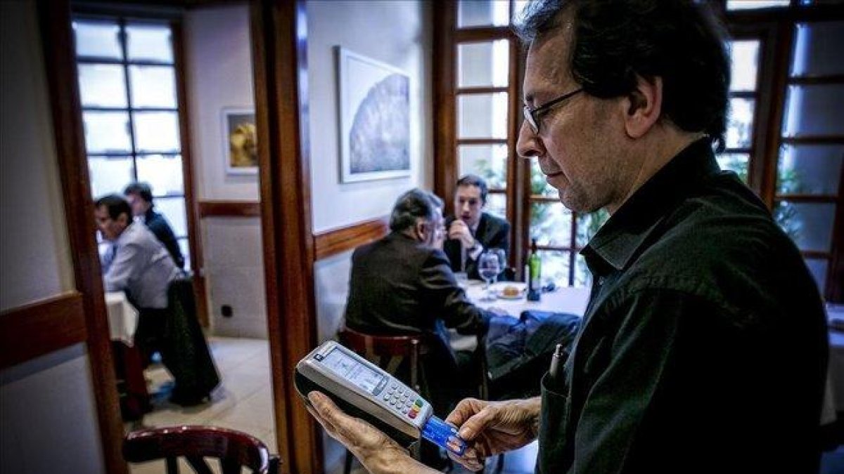 Un camarero cobra una cuenta en un restaurante de Barcelona.-JOAN CORTADELLAS