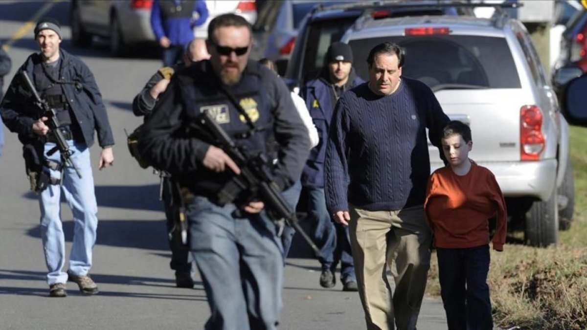 Agentes de policía custodian a padres e hijos de la escuela de Newtown tras la matanza del 2012.-AP / JESSICA HILL