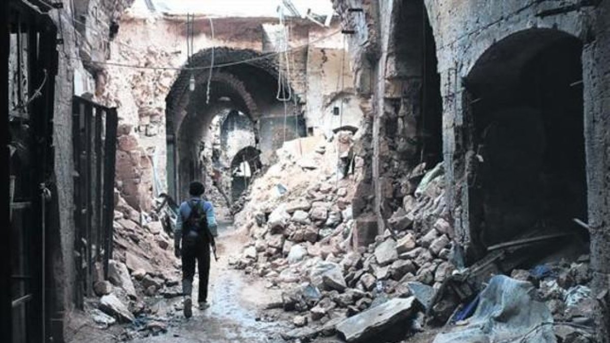 Un miliciano camina por entre las ruinas que han dejado los bombardeos en el zoco antiguo de Alepo, una ciudad habitada desde hace 7.000 años.-AFP / ZEIN AL RIFAI