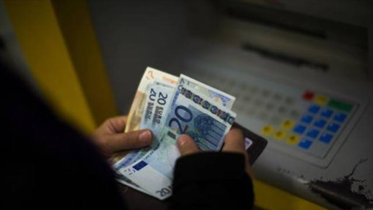 Una mujer saca dinero de un cajero automático. 