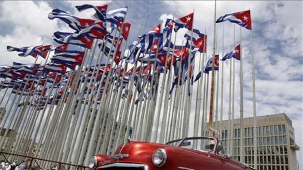 Un coche clásico americano pasa al lado de la embajada estadounidense en La Habana, donde ondean decenas de banderas de Cuba.-AP / DESMOND BOYLAN