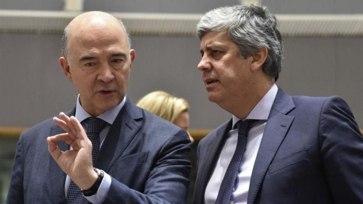 El comisario europeo de Economía, Pierre Moscovici, conversa con el ministro portugés de Finanzas, Mario Centeno, este martes en Bruselas.-JOHN THYS / AFP