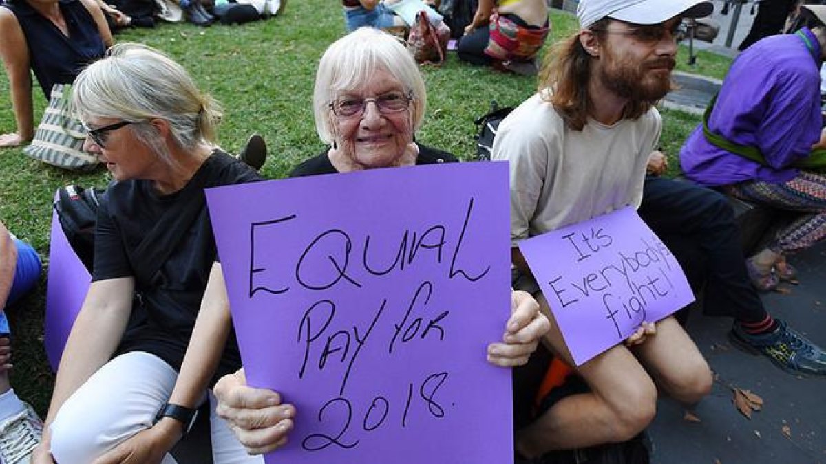 Una australiana pide igual salario para mujeres y hombres, junto a un joven que subraya que es una lucha de todos, en la concentración del Día de la Mujer en Melbourne.-EFE / JOE CASTRO
