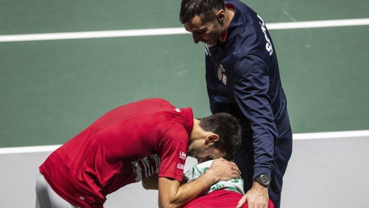 Djokovic (i) consuela a Troicki en el banquillo serbio tras perder ante Rusia.-AP