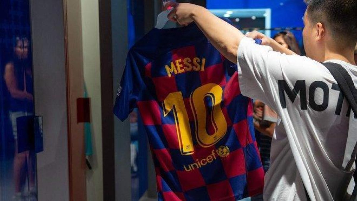 Un aficionado mira una camiseta de Messi, este viernes en la tienda del Barça.-AFP / JOSEP LAGO