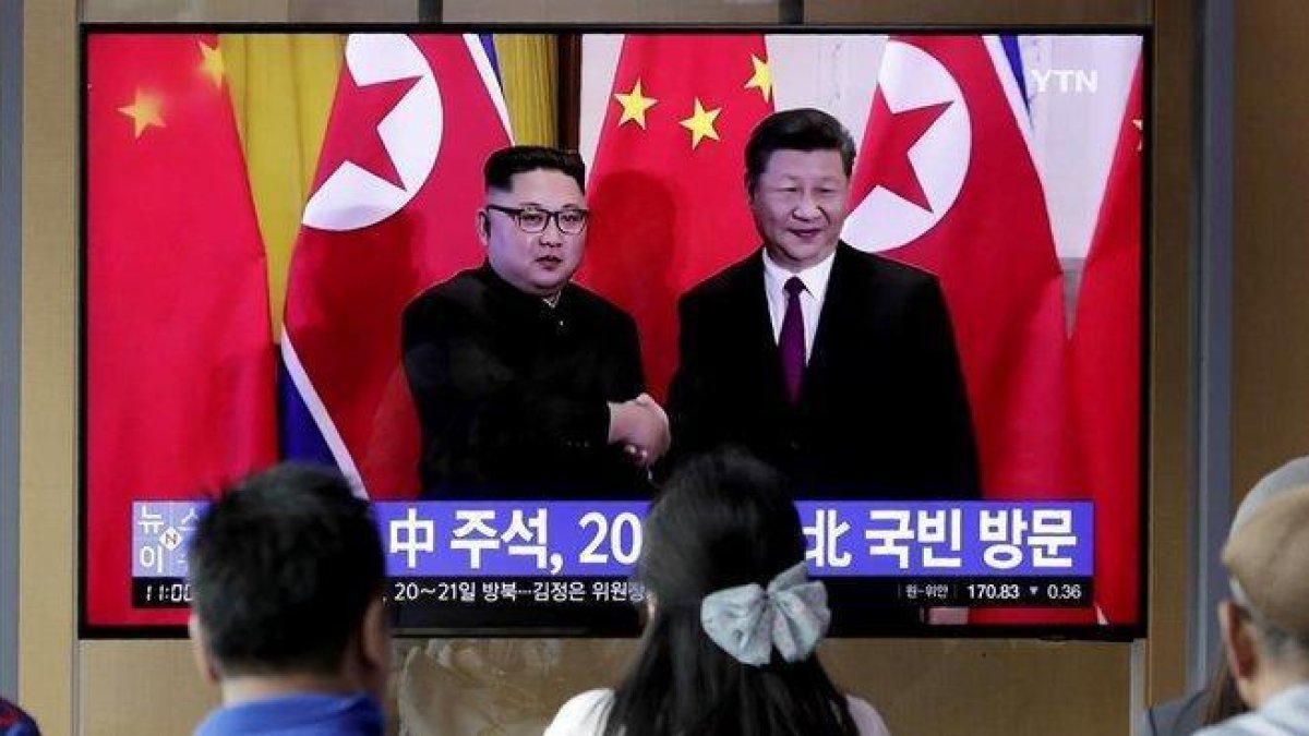 Unos transeúntes observan un programa de TV en el que aparecen el presidente chino Xi Jinping saludando al líder norcoreano Kim Jong-un en Pionyang.-LEE JIN-MAN (AP)