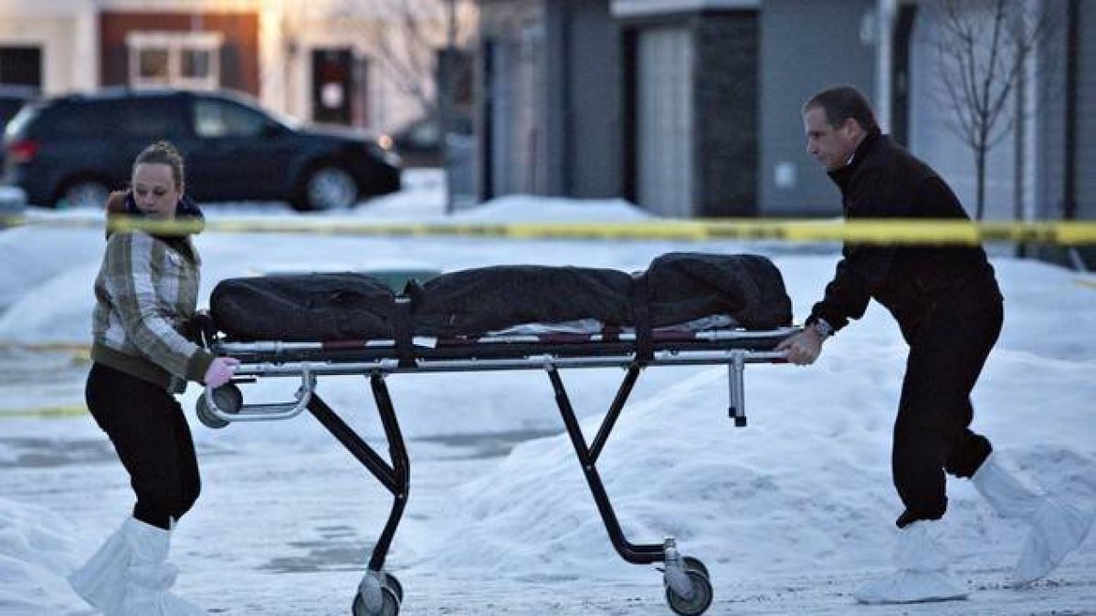 Dos agentes se llevan uno de los cadáveres encontrados en una casa de Edmonton, este martes.-Foto:   AP / JASON FRANSON