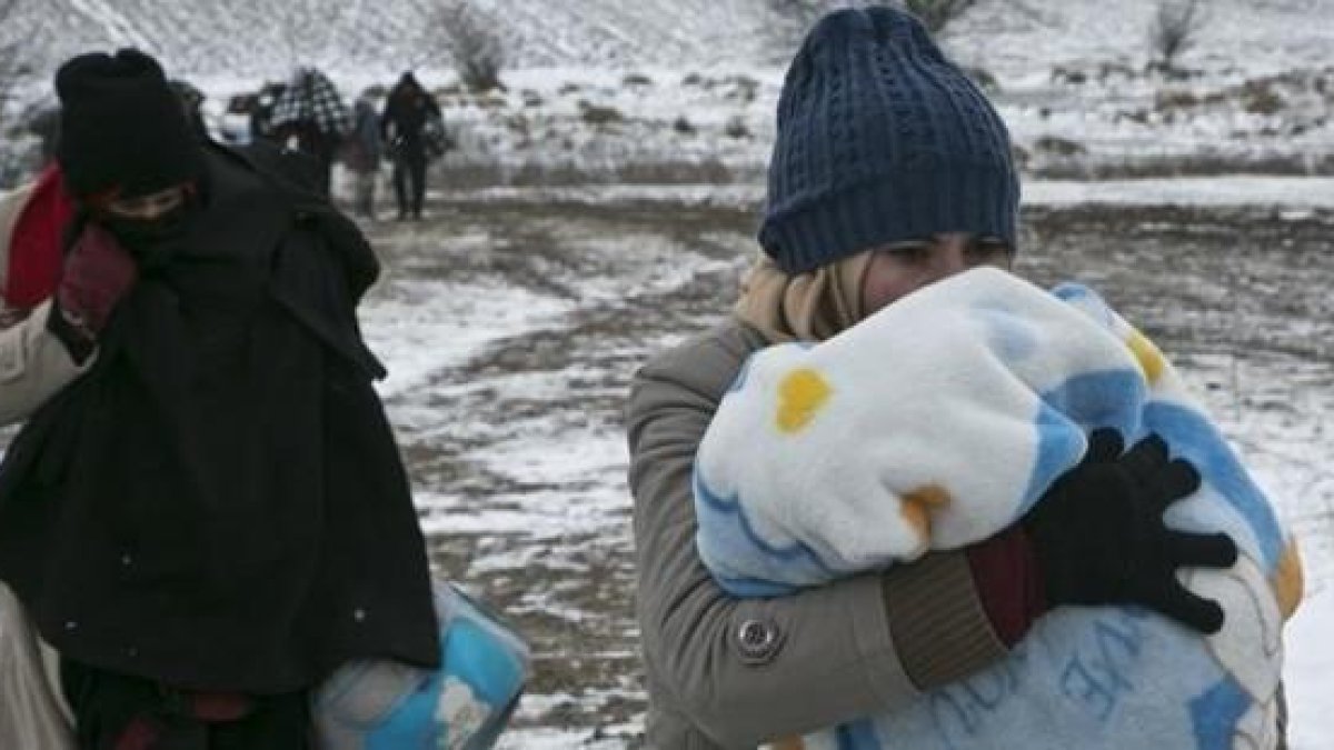 Una mujer migrante protege a su hijo con una manta mientras camina cerca de Miratovac (Serbia), este lunes.-AP / VISAR KRYEZIU