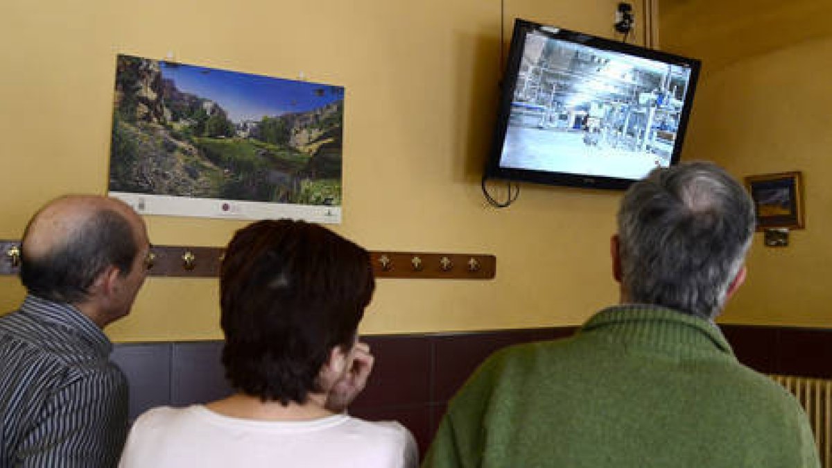 Vecinos de San Leonardo siguen en la Televisión de un bar la noticia sobre los despidos de Norma. / ÁLVARO MARTÍNEZ-