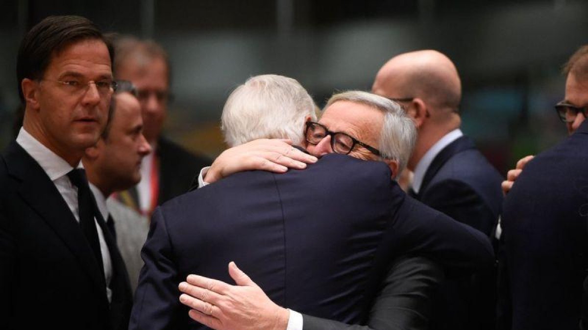 Juncker abraza a Barnier (de espaldas), a su llegada a la cumbre del Consejo Europeo, este domingo en Bruselas.-AFP