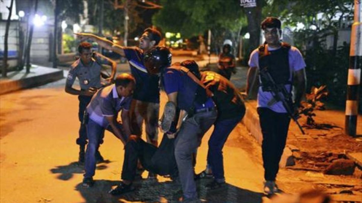 Un grupo de personas ayudan a un herido en el tiroteo en un restaurante de la zona diplomática de Dacca, capital de Bangladés.-AP