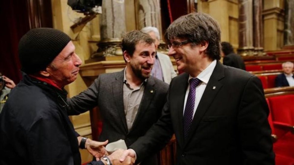 El 'president' Puigdemont saluda a Lluís Llach en el Parlament.-JOAN CORTADELLAS