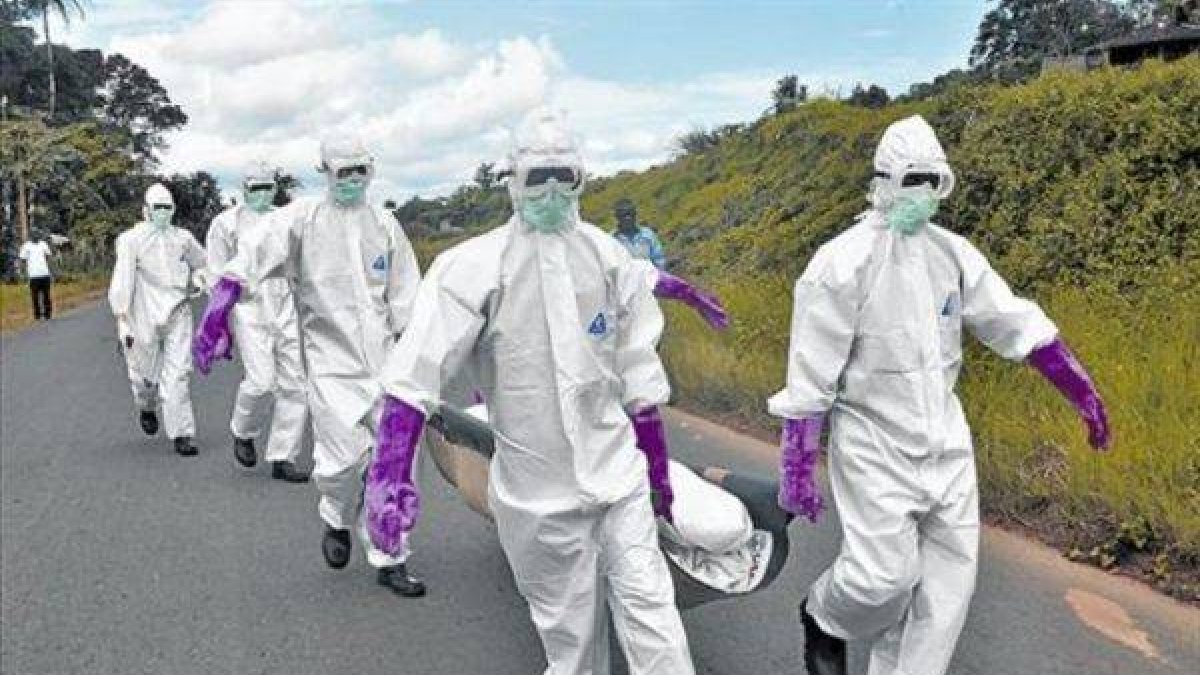 Personal protegido con trajes especiales retira el cuerpo de un fallecido por ébola en Monrovia (Liberia), el sábado.-Foto: AP / ABBAS DULLEH