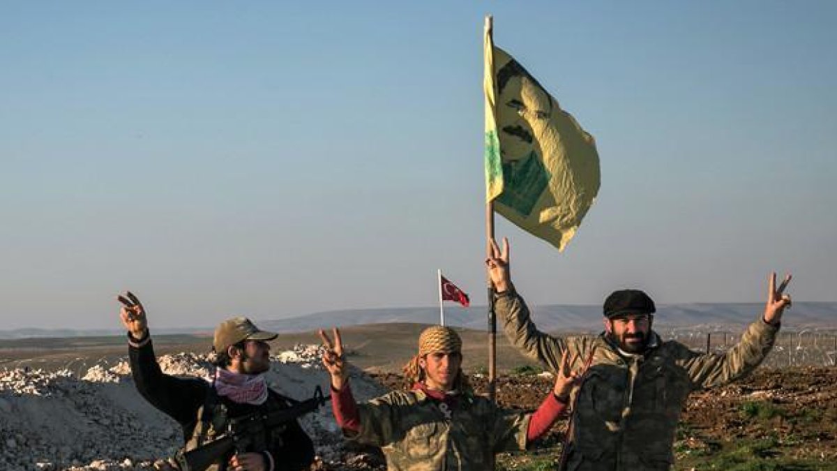 Milicianos kurdos con una bandera del líder del PKK, Abdulá Ocalán, en las cercanías de la ciudad siria de Alepo.-AP / MURSEL COBAN