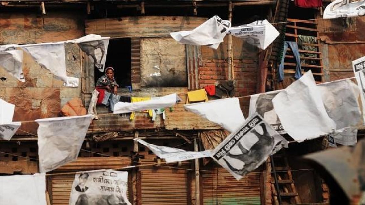 Vecinos del barrio de Shanty, Bangladesh, rodeados de publicidad electoral.-