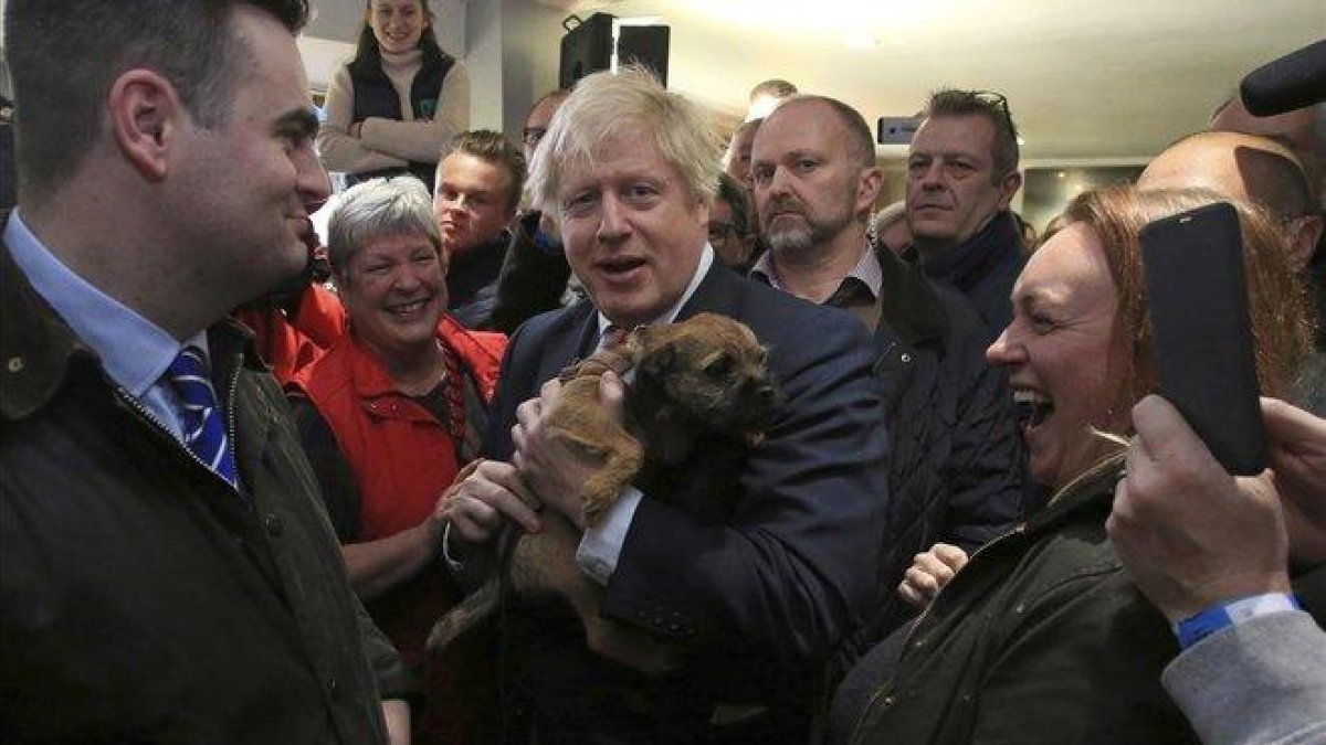 El primer ministro británico, Boris Johnson, sostiene un perro durante un encuentro con Paul Howell, el recién elegido diputado del Partido Conservador en Sedgefield, en el noreste de Inglaterra.-LINDSEY PARNABY (AP)