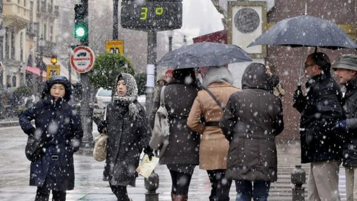 Varias personas pasean por una céntrica calle de Granada a pesar de la nieve que ha caído en las últimas horas en la ciudad, donde se ha declarado la alerta amarilla debido a las consecuencia del temporal de viento, frío y nieve que afecta a casi todo el -MIGUEL ÁNGEL MOLINA / EFE