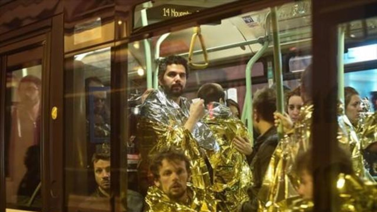 Evacuación 8 Varias personas abandonan la zona de El Bataclan en autobús y cubiertos con mantas de aluminio.-EFE