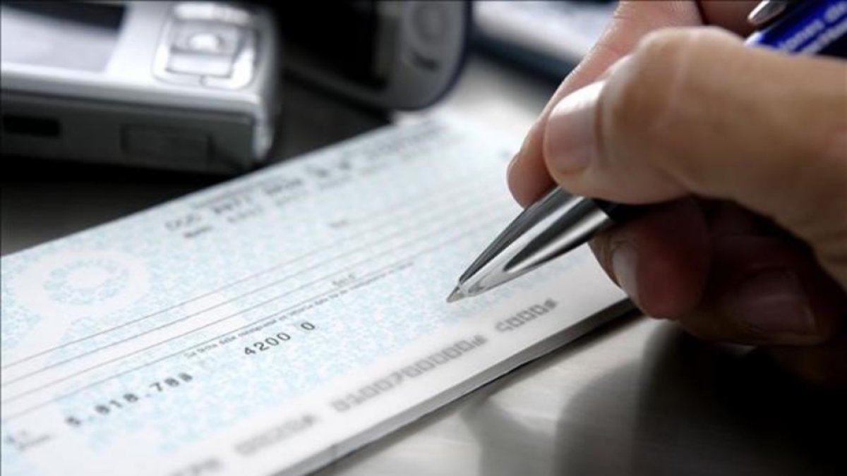 Firma de un cheque en una entidad bancaria.-123RF