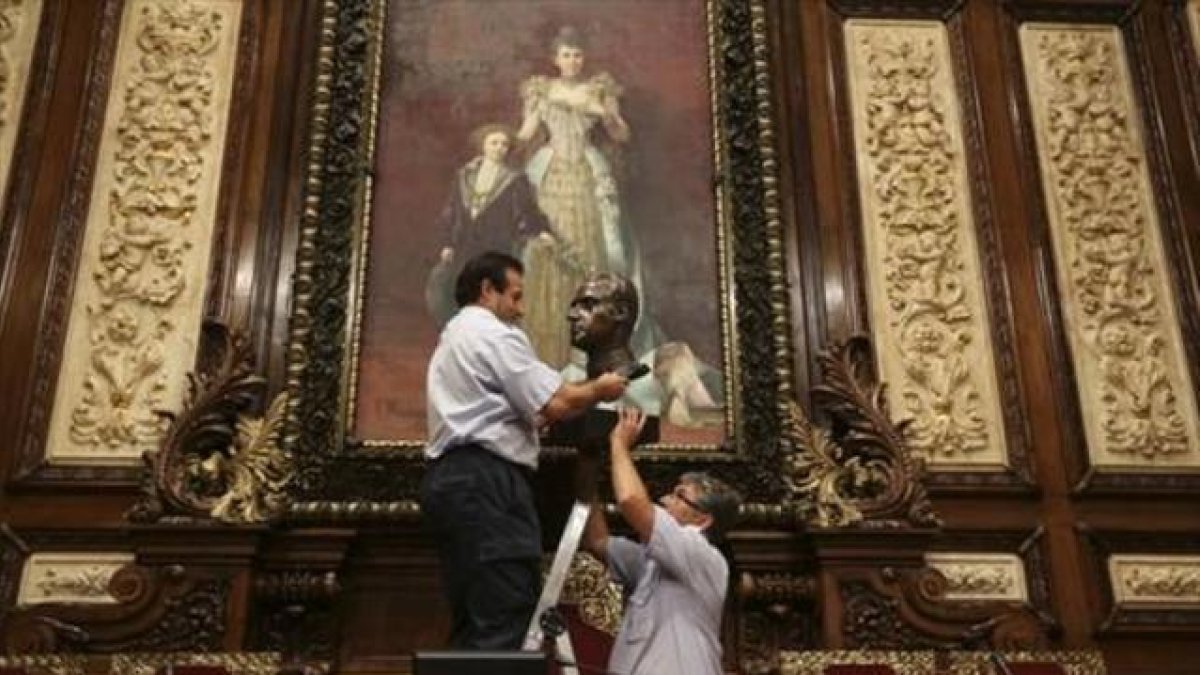 Dos trabajadores municipales retiran el busto del rey Juan Carlos I, en julio.-DANNY CAMINAL