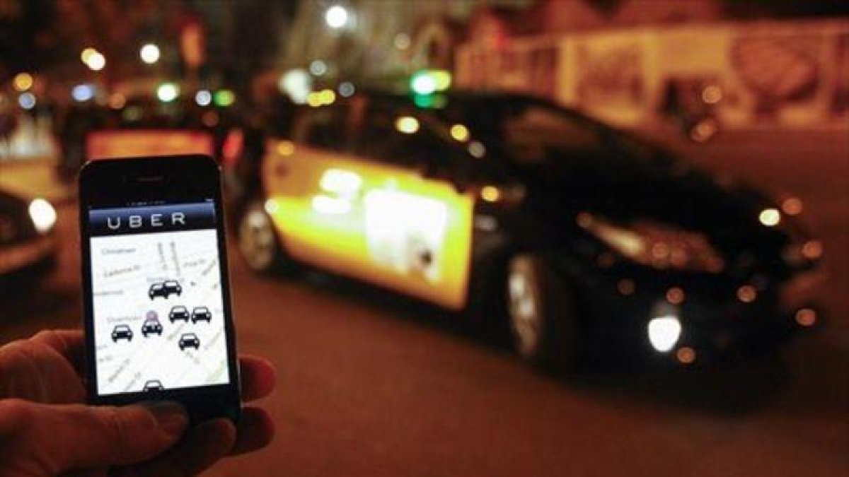 Un usuario consulta la aplicación de Uber junto a la Sagrada Família, en diciembre del 2014.-AFP / QUIQUE GARCIA