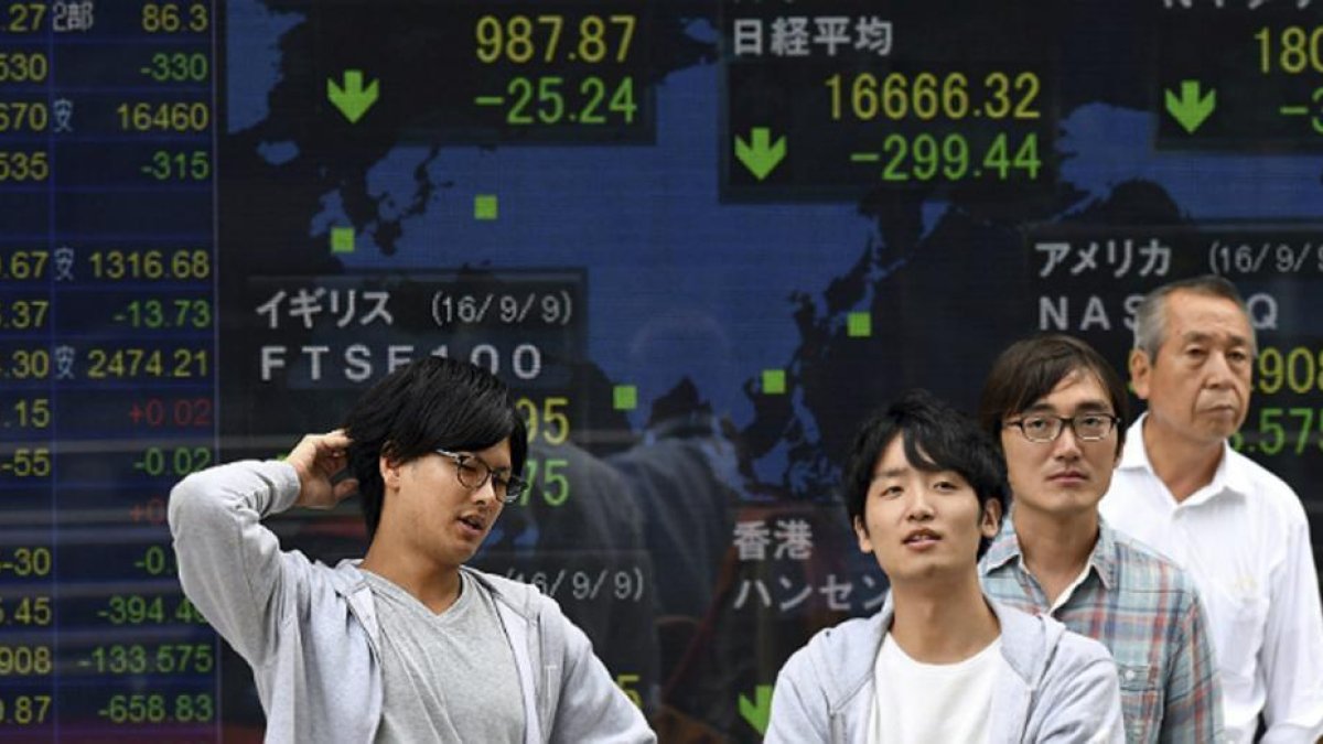 Japoneses en Tokio ante un monitor con la evolución de la bolsa.-EFE / FRANK ROBICHON
