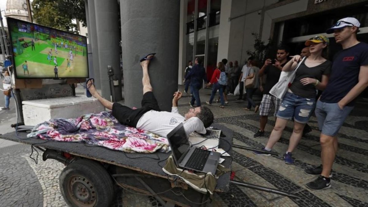 Unos turistas ven los Juegos en una calle de Río.-EFE / BARBARA WALTON