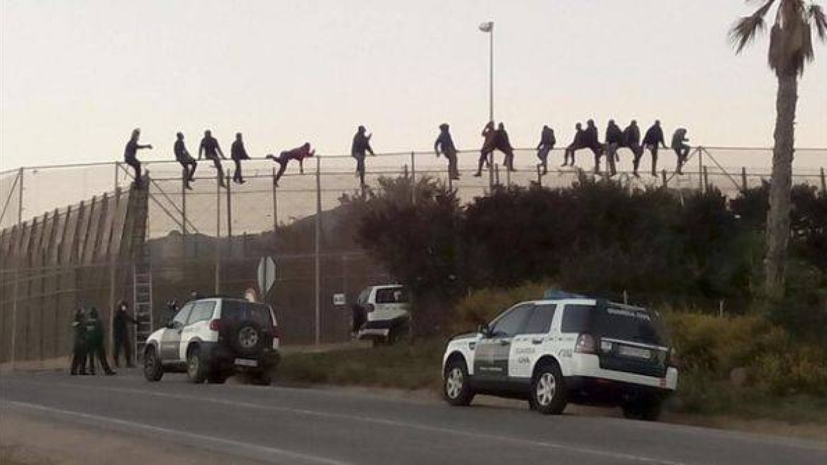 Al menos una quincena de inmigrantes permanecen encaramados en la valla de Melilla en las proximidades del cementerio musulmán.-Foto: EFE / NOELIA RAMOS