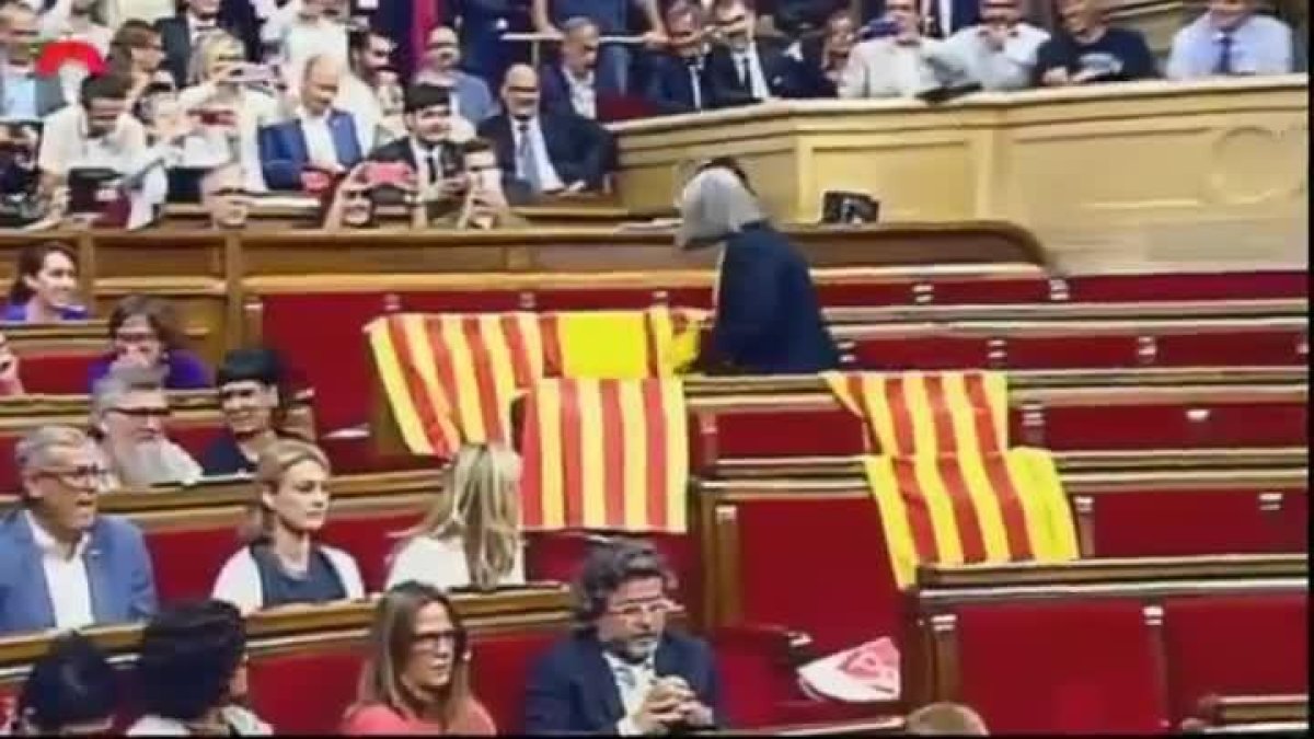 La diputada de Catalunya Sí que es Pot Àngels Martínez retira las banderas de España que habían dejado en su escaño los diputados del PP.-EL PERIÓDICO