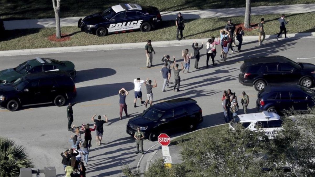 Evacuación de estudiantes con los brazos en alto a la salida del instituto Marjory Stoneman Douglas, en Parkland (Florida), el 14 de febrero.-AP