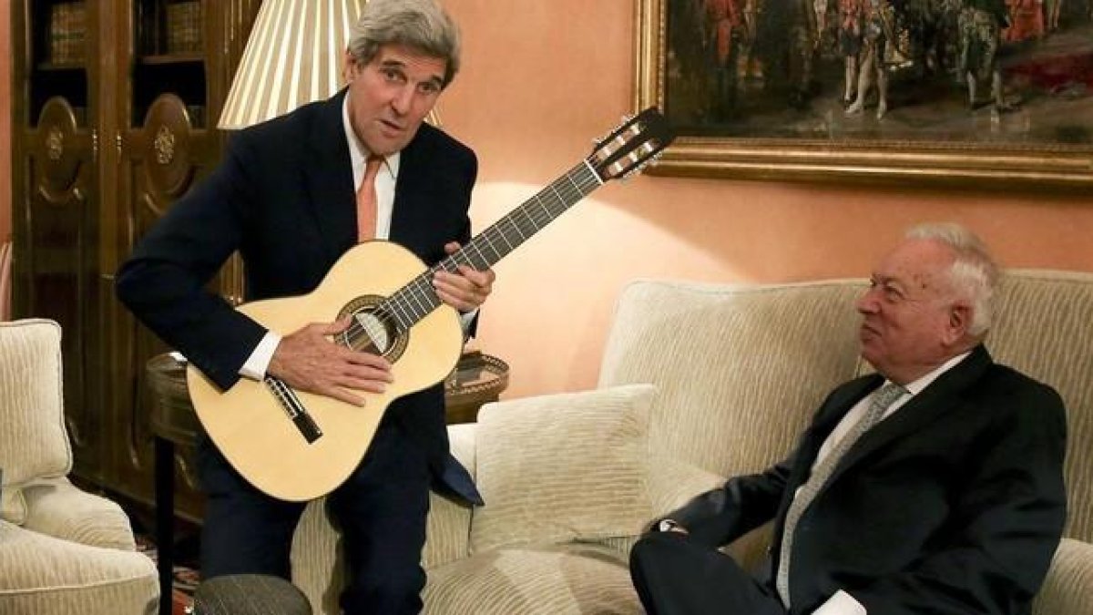 Kerry con la guitarra española que le ha regalado Margallo, sentado en el sofá, esta tarde en el Palacio de Viana, en Madrid.-EFE / BALLESTEROS