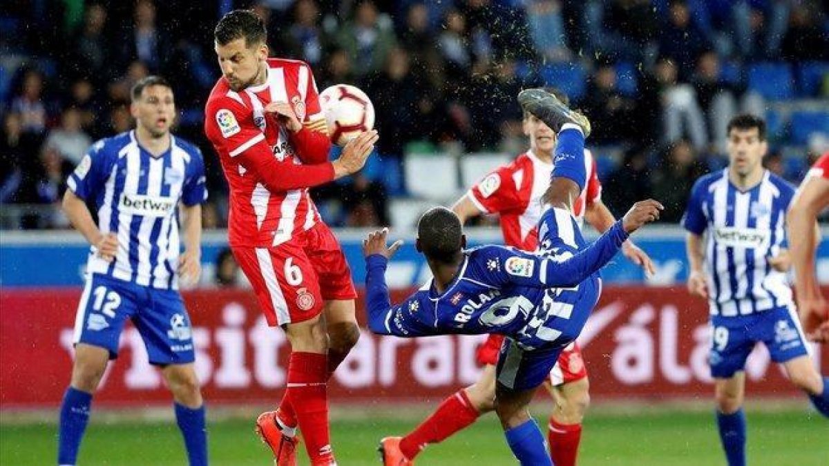 El delantero uruguayo del Alavés Diego Rolan remata ante el centrocampista del Girona Alex Granell.-