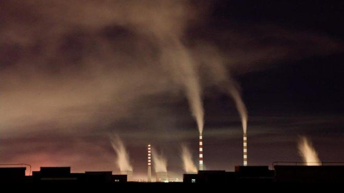 Chimeneas de una planta de energia de carbon emiten humo durante la noche en Changchun  en China-