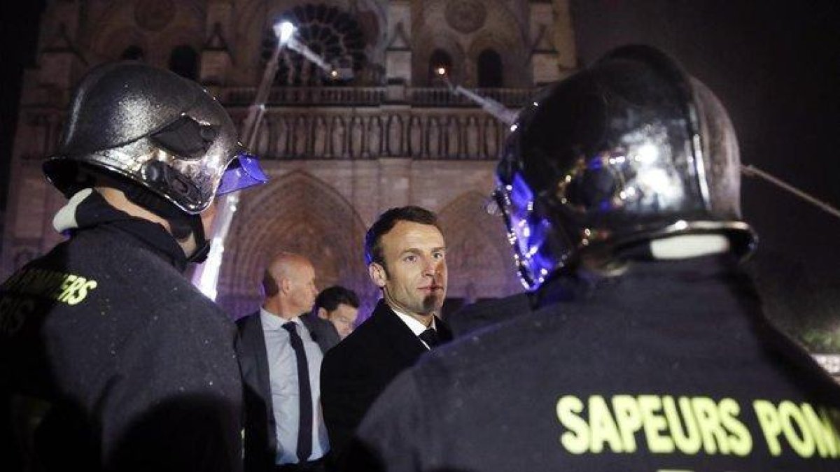 El presidente de Francia Emmanuel Macron, habla con los bomberos que intentan apagar el incendio en la catedral de Notre Dame, en París, el pasado abril.-YOAN VALAT (EFE)