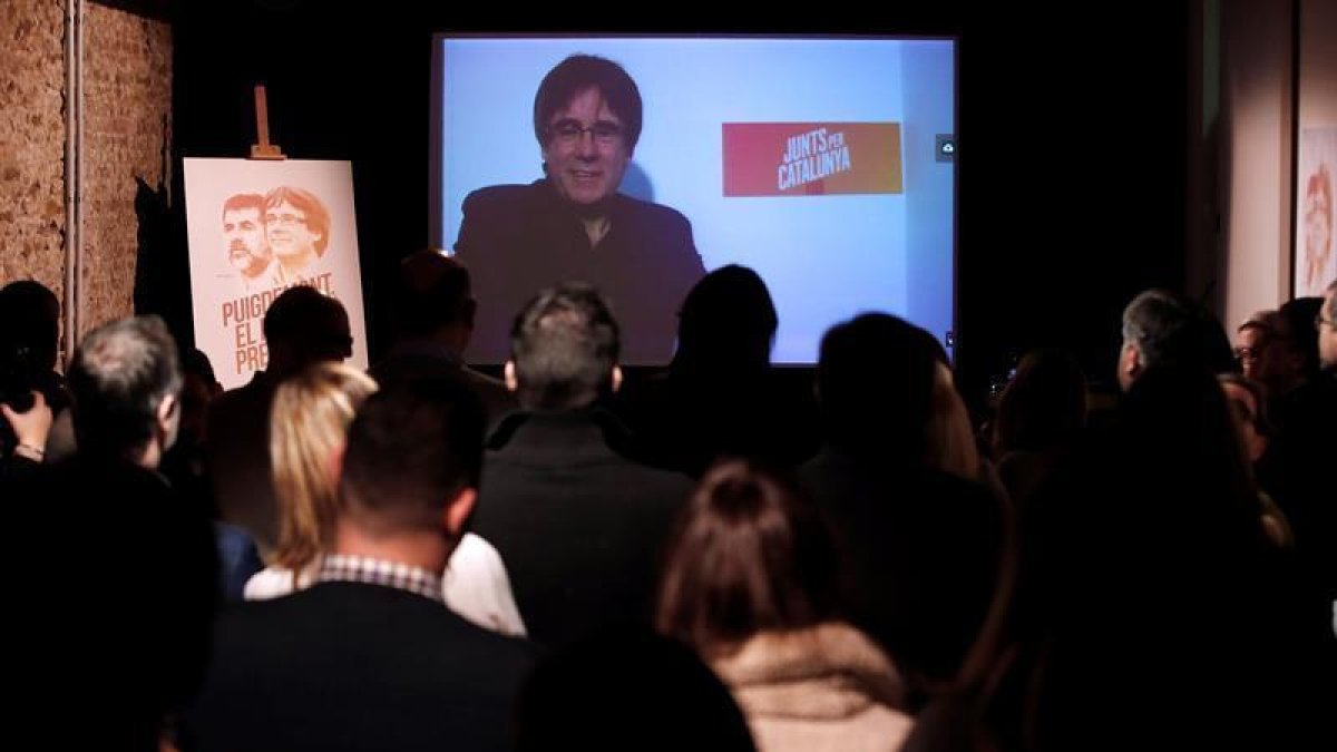 El expresidente de la Generalitat, Carles Puigdemont, conversa por videoconferencia con candidatos y simpatizantes durante la inauguración de la sede de campaña de Junts per Catalunya.-EFE
