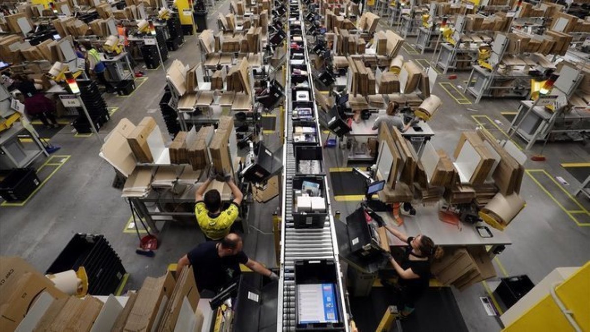 Trabajadores en una planta empaquetadora de pedidos de Amazon.-REUTERS