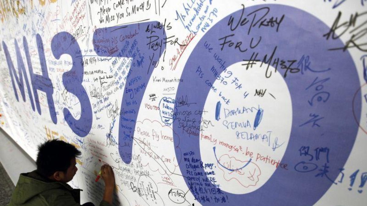 Fotografía de archivo del 13 de marzo del 2014 de un hombre escribiendo mensajes en recuerdo a las víctimas del vuelo MH370 de Malaysia Airlines en el aeropuerto internacional de Kuala Lumpur (Malasia).-EFE
