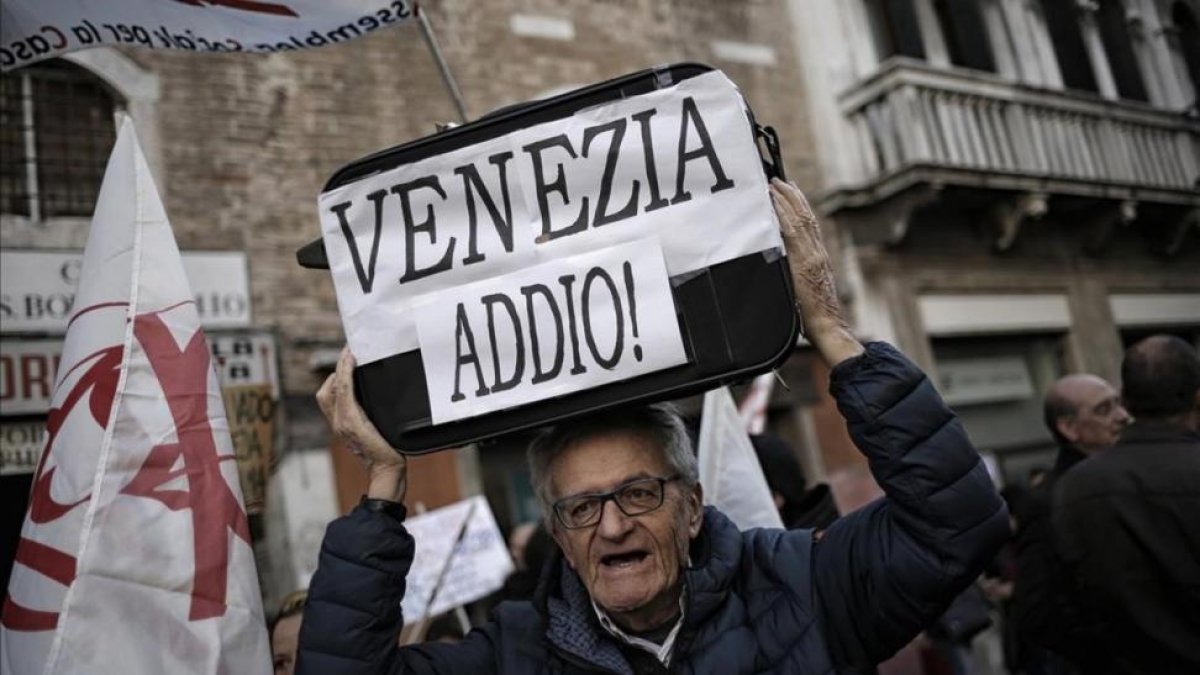 Uno de los participantes en la manifestación contra la despoblación del casco antiguo y el aumento descontrolado del turismo en Venecia.-AFP / MARCO BERTORELLO