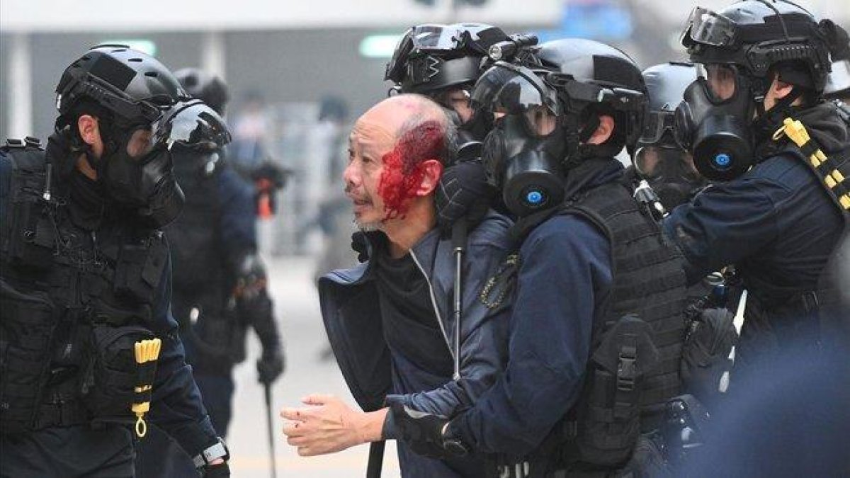 La policía se lleva a un manifestante herido en Hong Kong.-AFP / PHILIP FONG