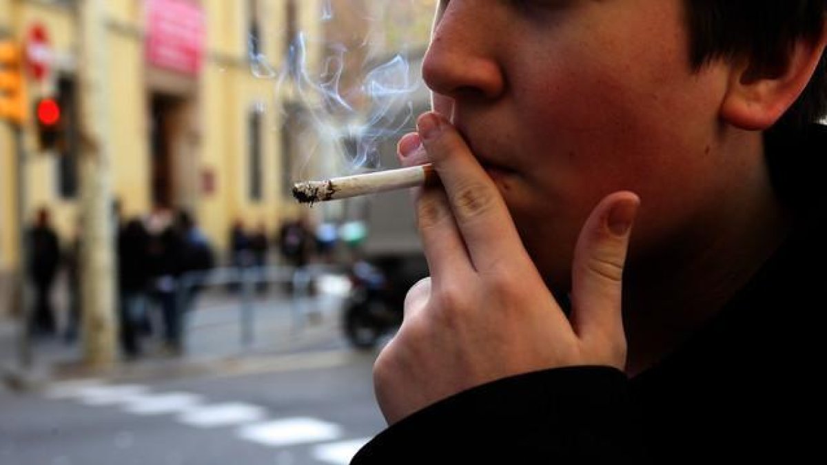 Un joven fumando un cigarro.-