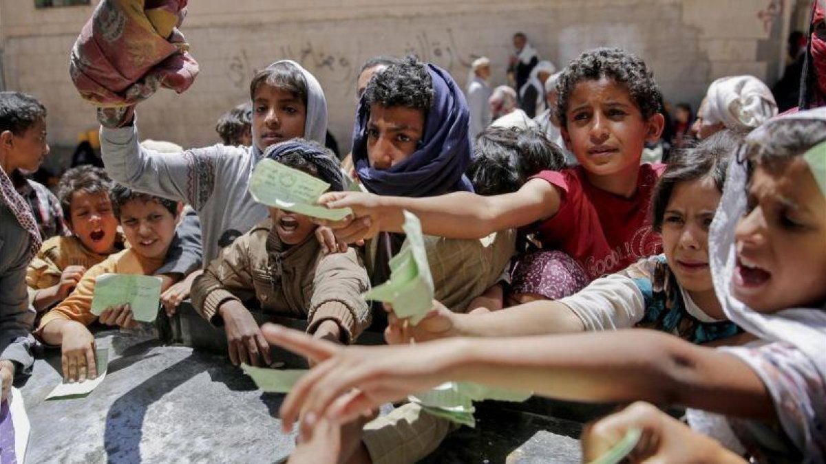 Niños yemenís presentan documentos para recibir las raciones de alimentos proporcionadas por una oenegé local en Saná.-HANI MOHAMMED (AP)