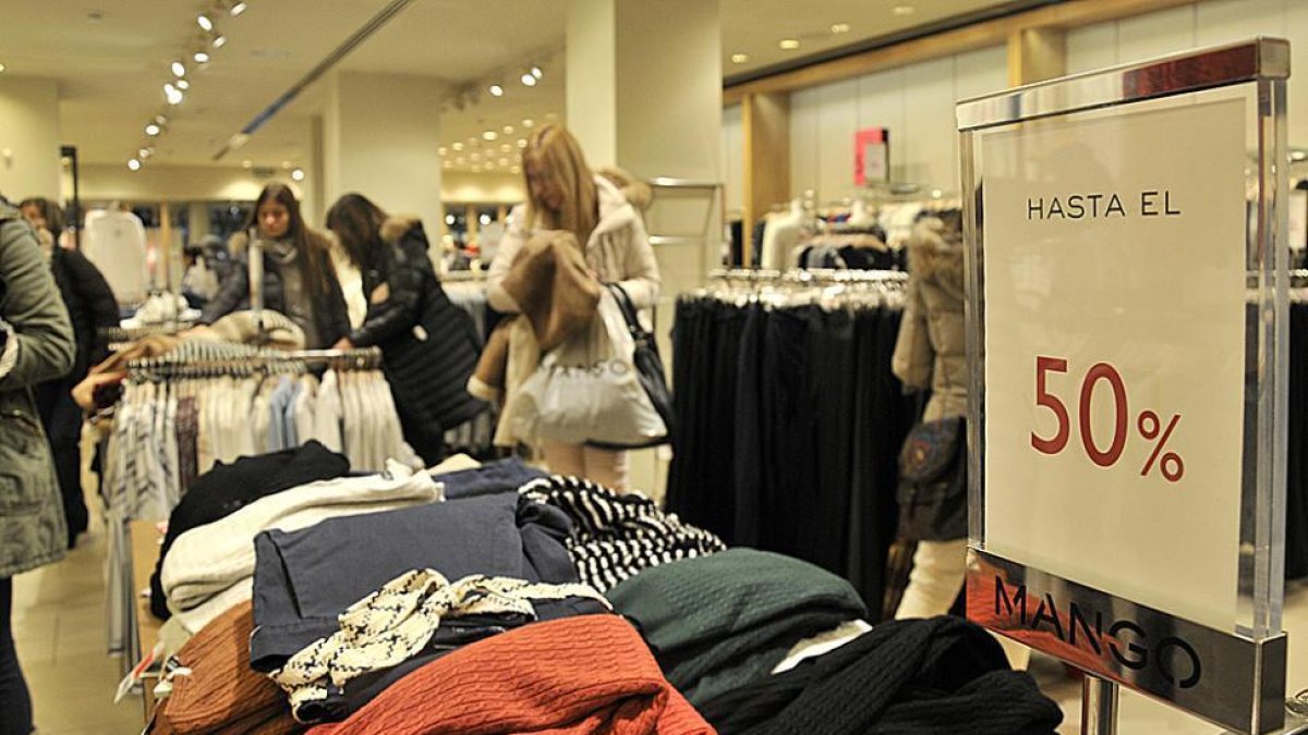 Varias personas observan el género en un comercio textil en Soria durante la mañana de ayer.-VALENTÍN GUISANDE