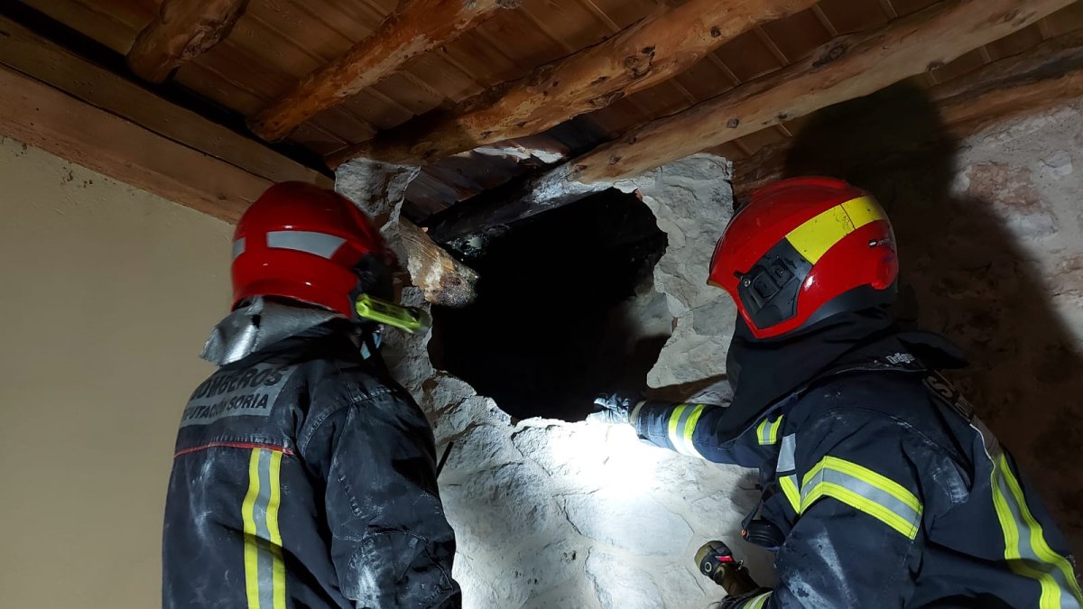 Los bomberos miran por un hueco abierto para extinguir el incendio en Castillejo de Robledo. HDS