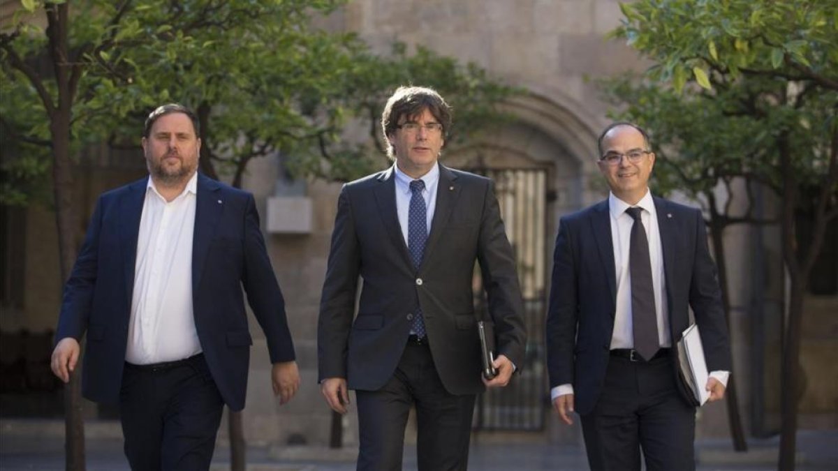 El president Carles Puigdemont, entre el vicepresidente Oriol Junqueras y el consejero Jordi Turull, en el Palau de la Generalitat.-ALBERT BERTRAN