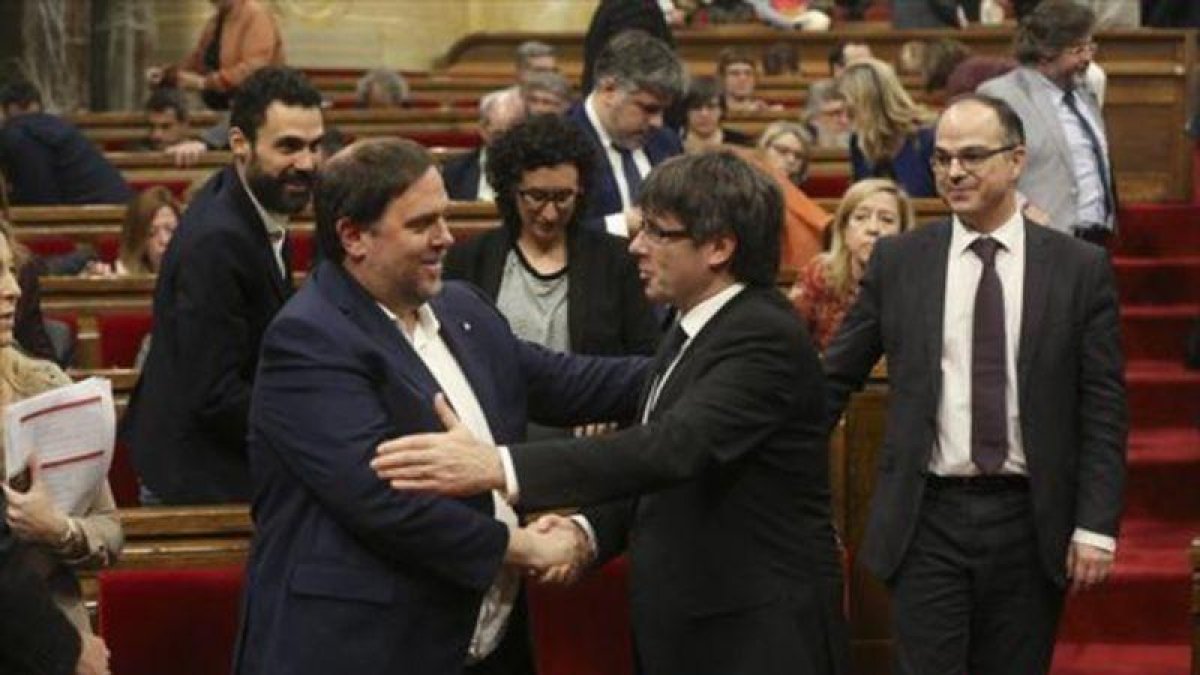 Junqueras y Puigdemont se saludan en el Parlament, en marzo.-DANNY CAMINAL