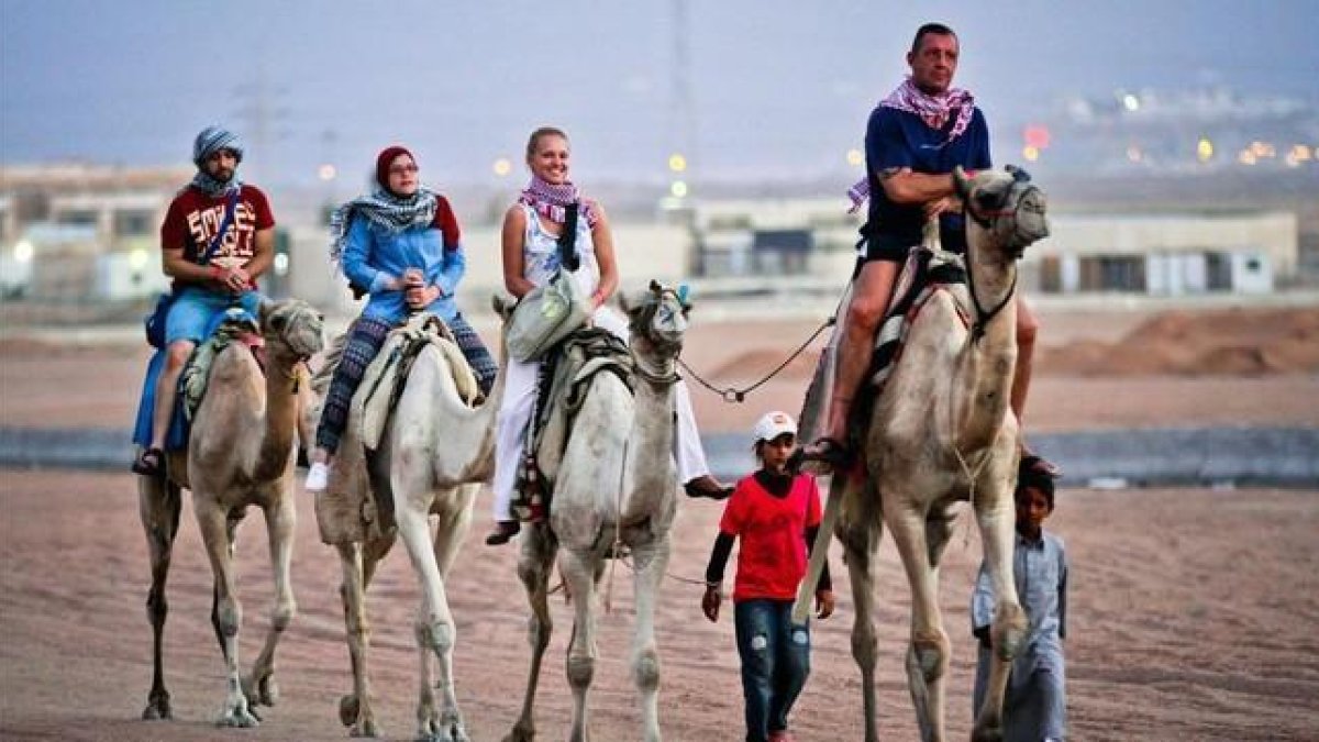 Turistas pasean en camellos en la ciudad egipcia de Sharm el Sheij.-AFP
