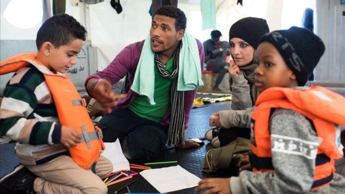 Fotografia cedida por la ONG Sea-Watch que muestra a Nasreen 2d y a su hijo Zizou i junto a otros inmigrantes a bordo del buque Sea Watch 3 en el mediterraneo el 23 de diciembre de 2018.-SEA WATCH
