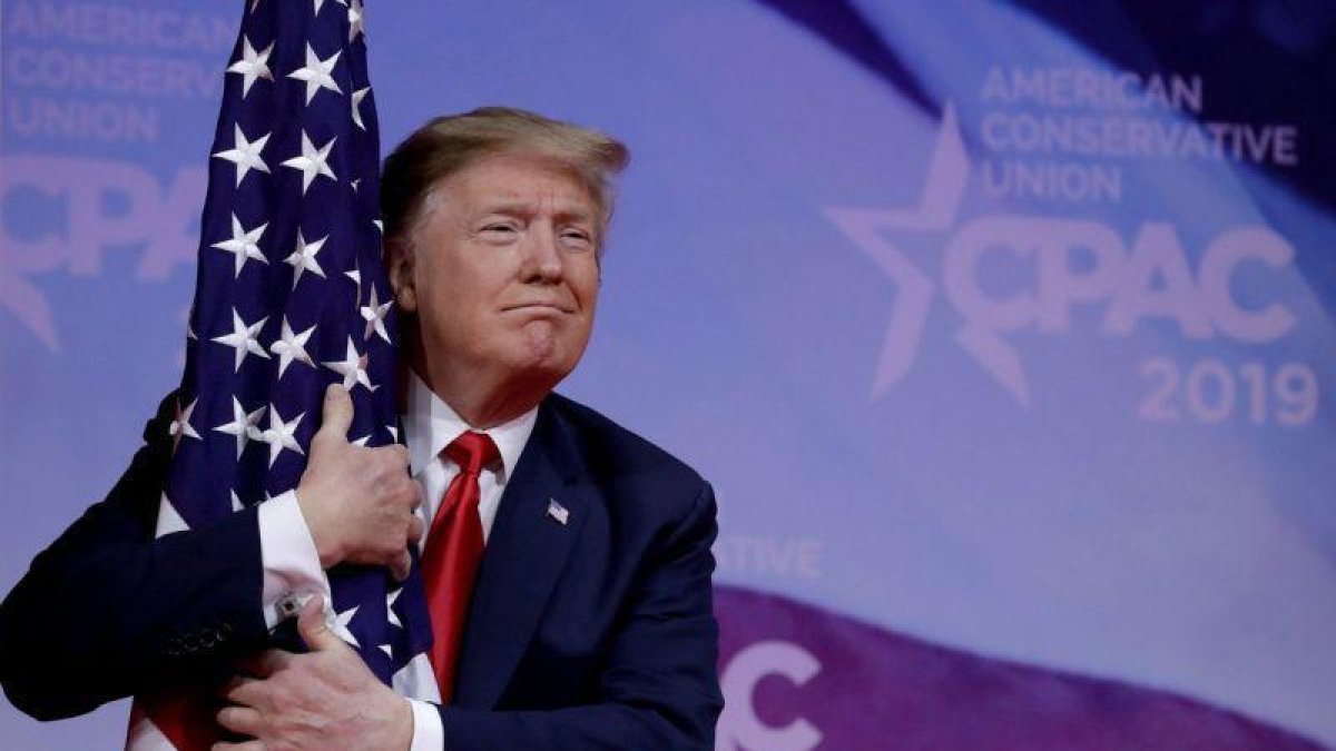 El presidente Donald Trump abrazando una bandera de su país.-REUTERS